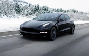 Tesla vehicle driving down snow covered road